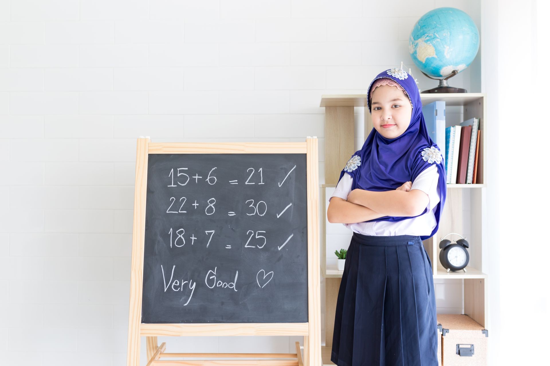 Islamic children feeling happy and smile in the classroom, muslim girl write number on blackboard, her answers is true, clever children